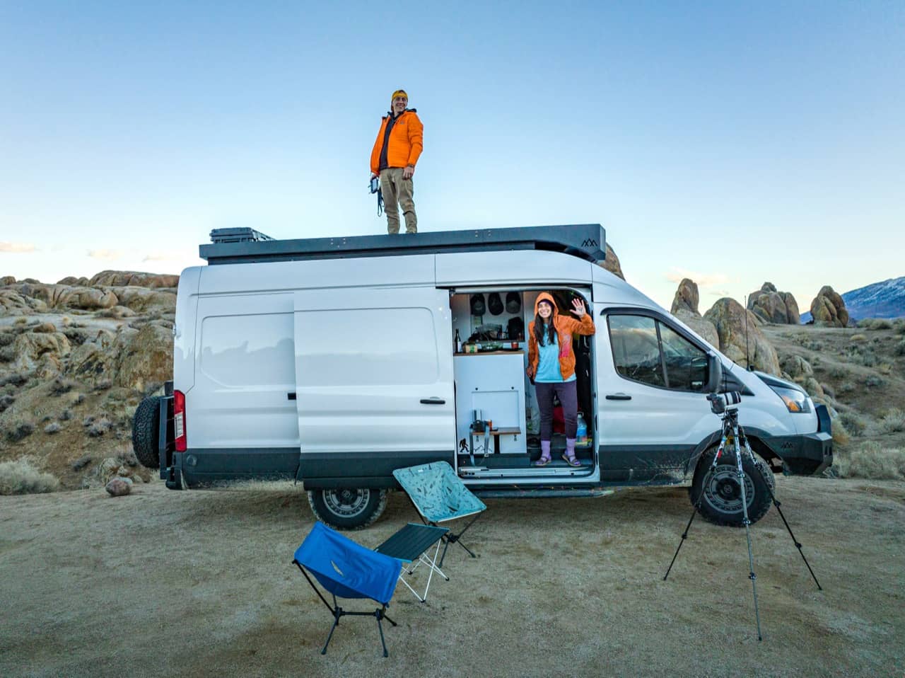 Kampeerders bij een omgebouwde camper geparkeerd in een rotsachtig landschap