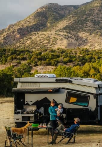 Gezin ontspant naast hun camper in de bergen